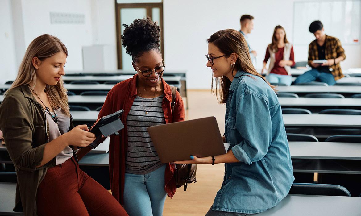 Alunos do Ensino Superior conversam entre si em sala de aula.