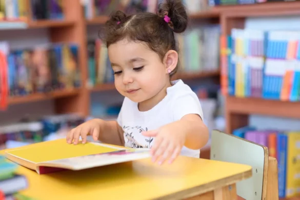 Criança estimulada ao hábito da leitura folheia livro infantil.